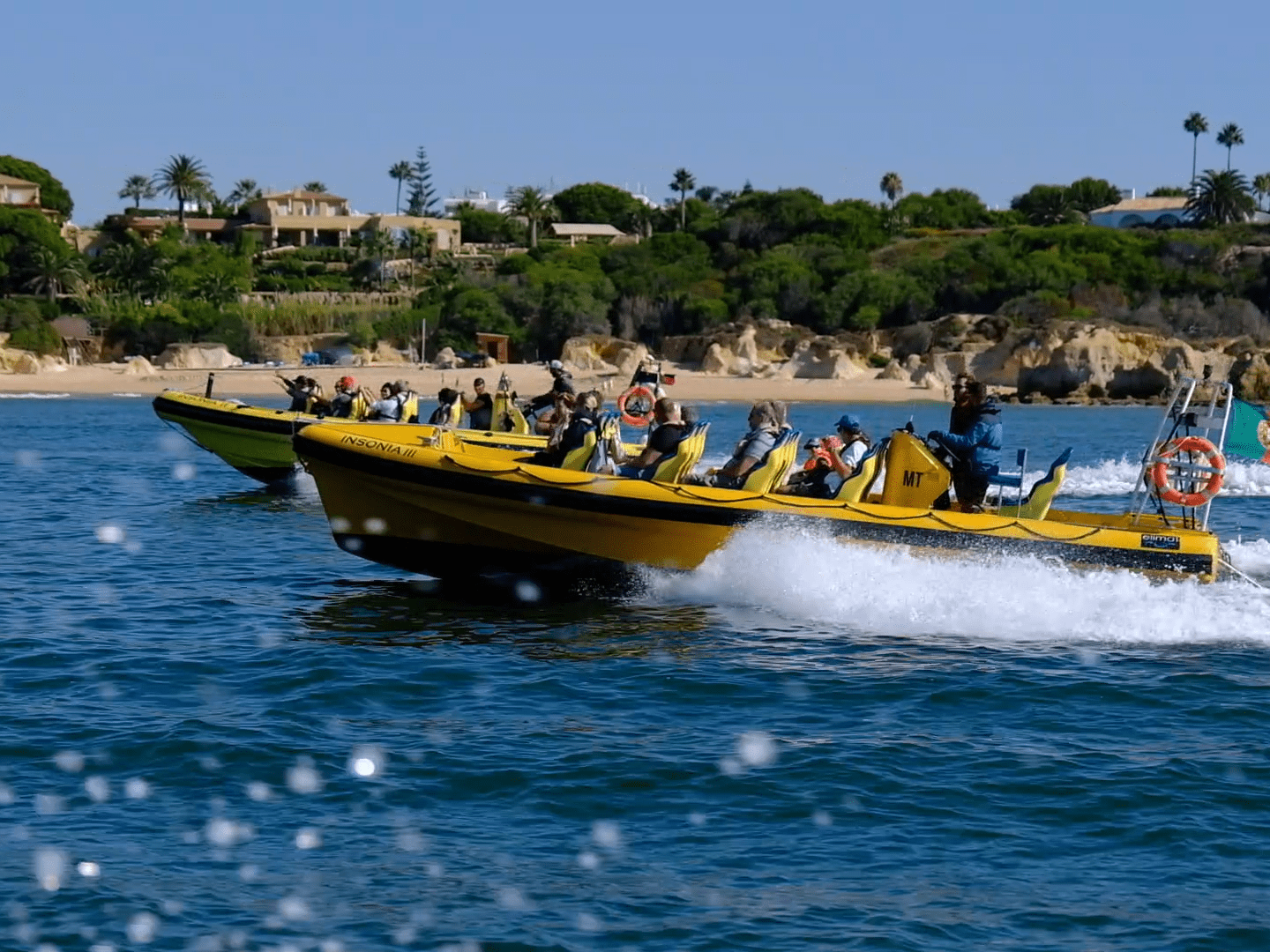 a group of people riding on the back of a boat in the water